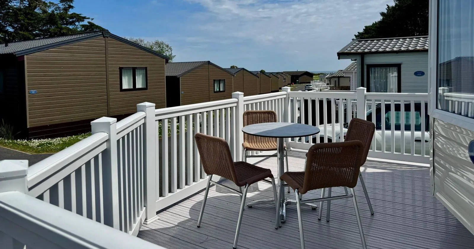 Private decking area with outdoor table and chairs at a modern holiday lodge