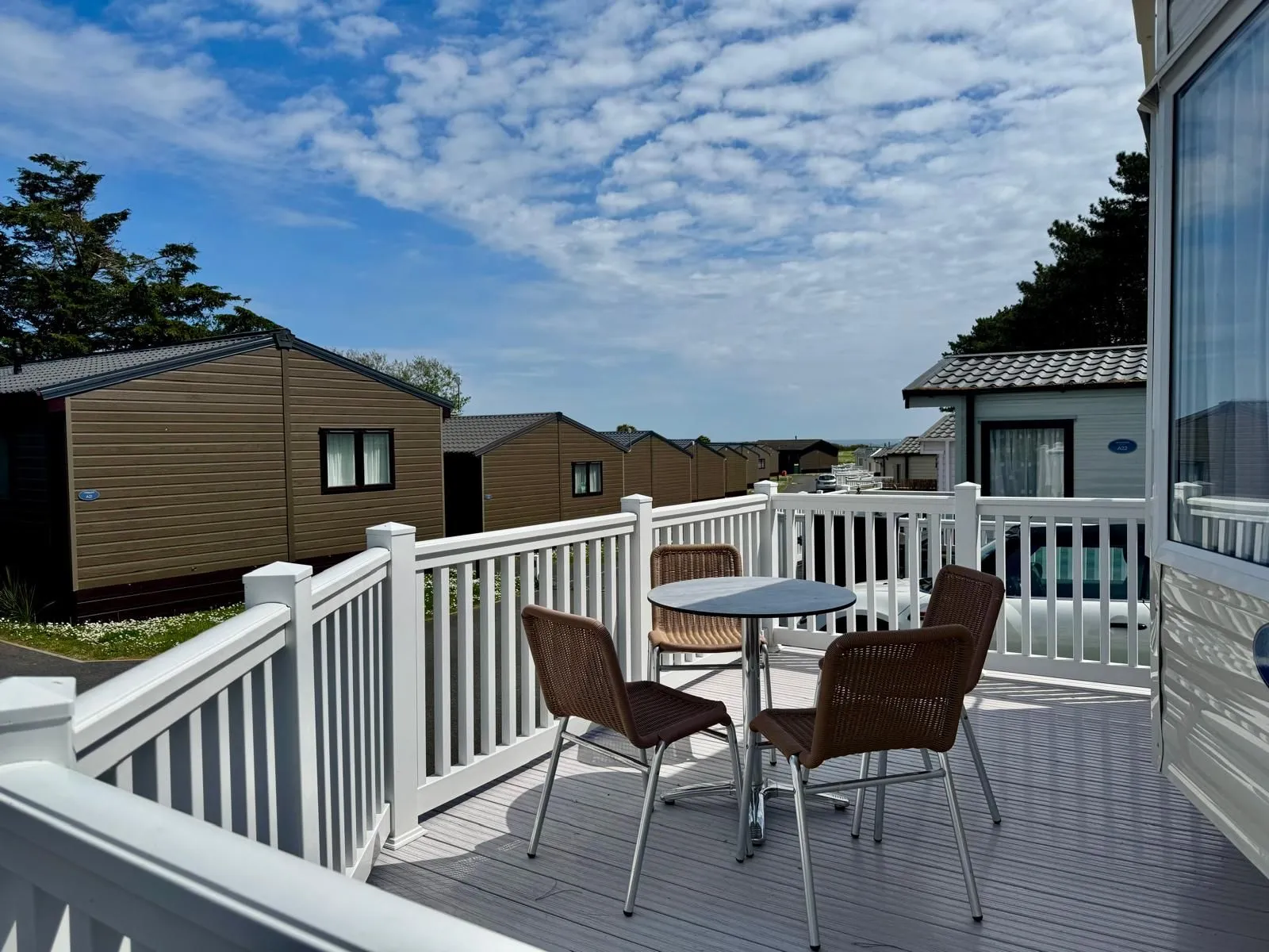 Private decking area with outdoor table and chairs at a modern holiday lodge