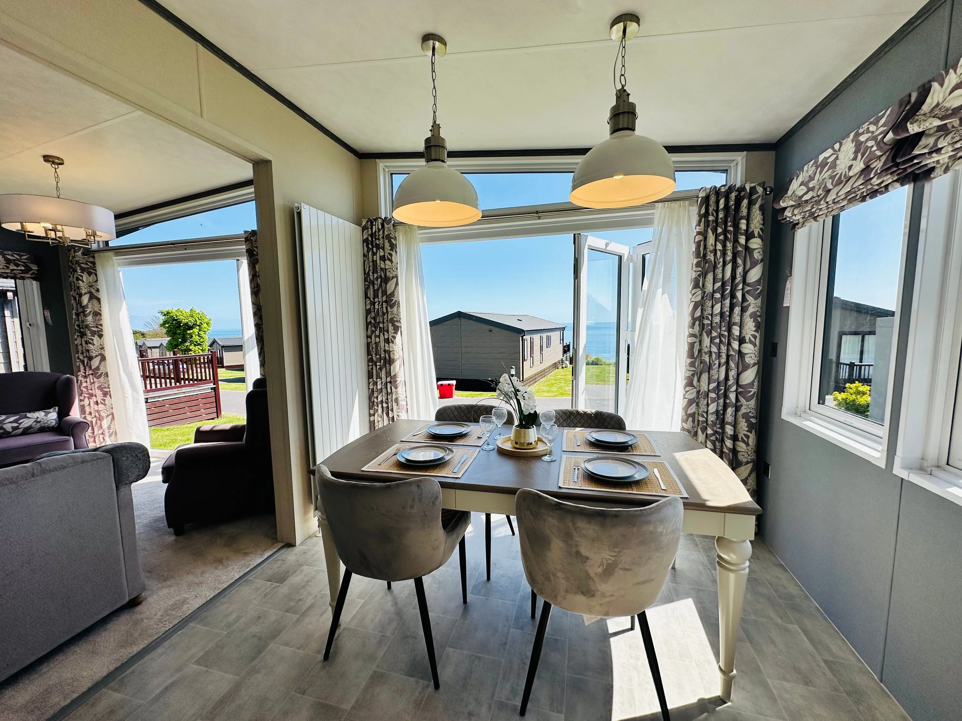 Modern caravan dining area with sea view through open patio doors