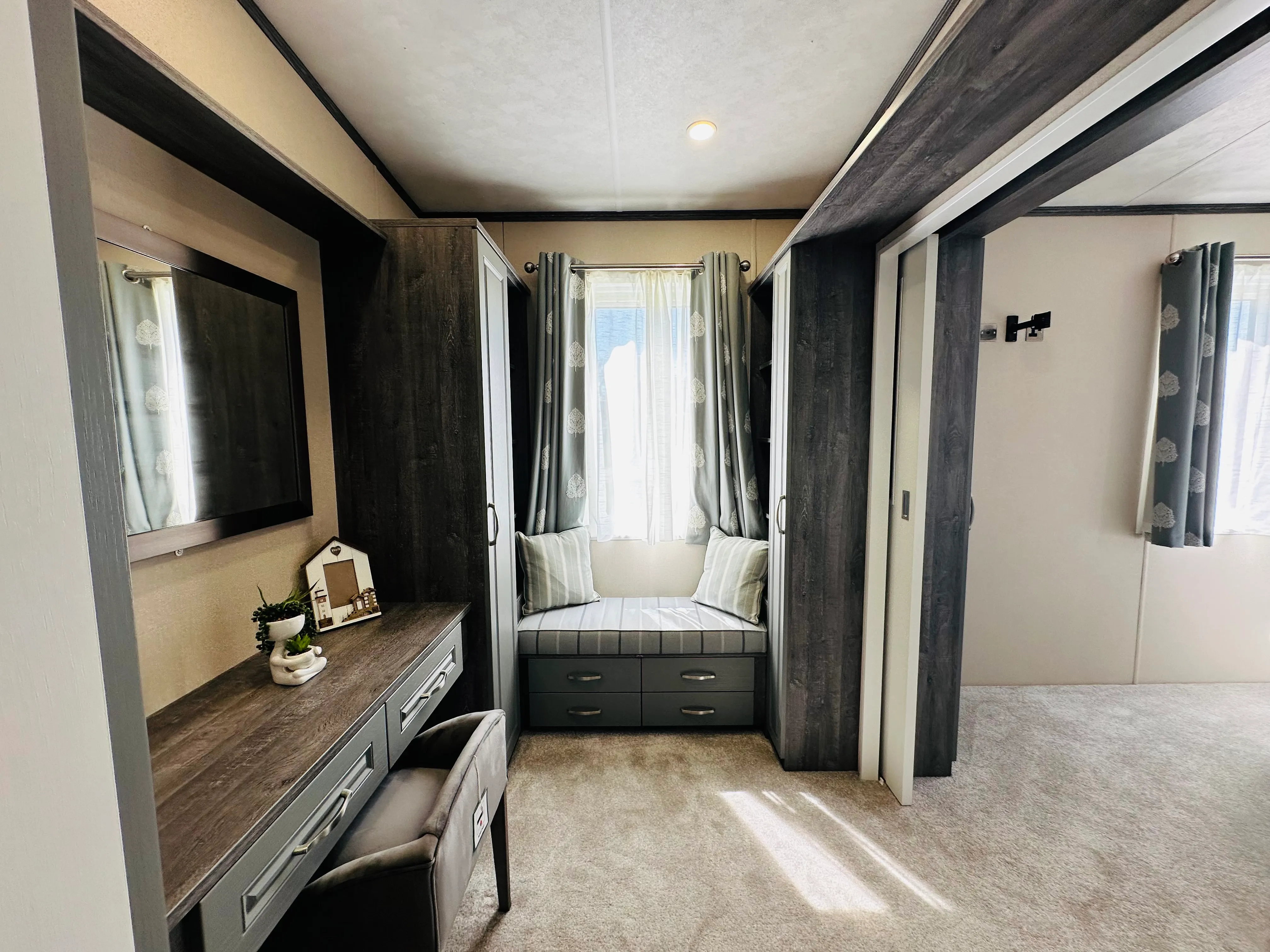 Modern bedroom dressing area with built-in wardrobes, vanity desk and cushioned window seat