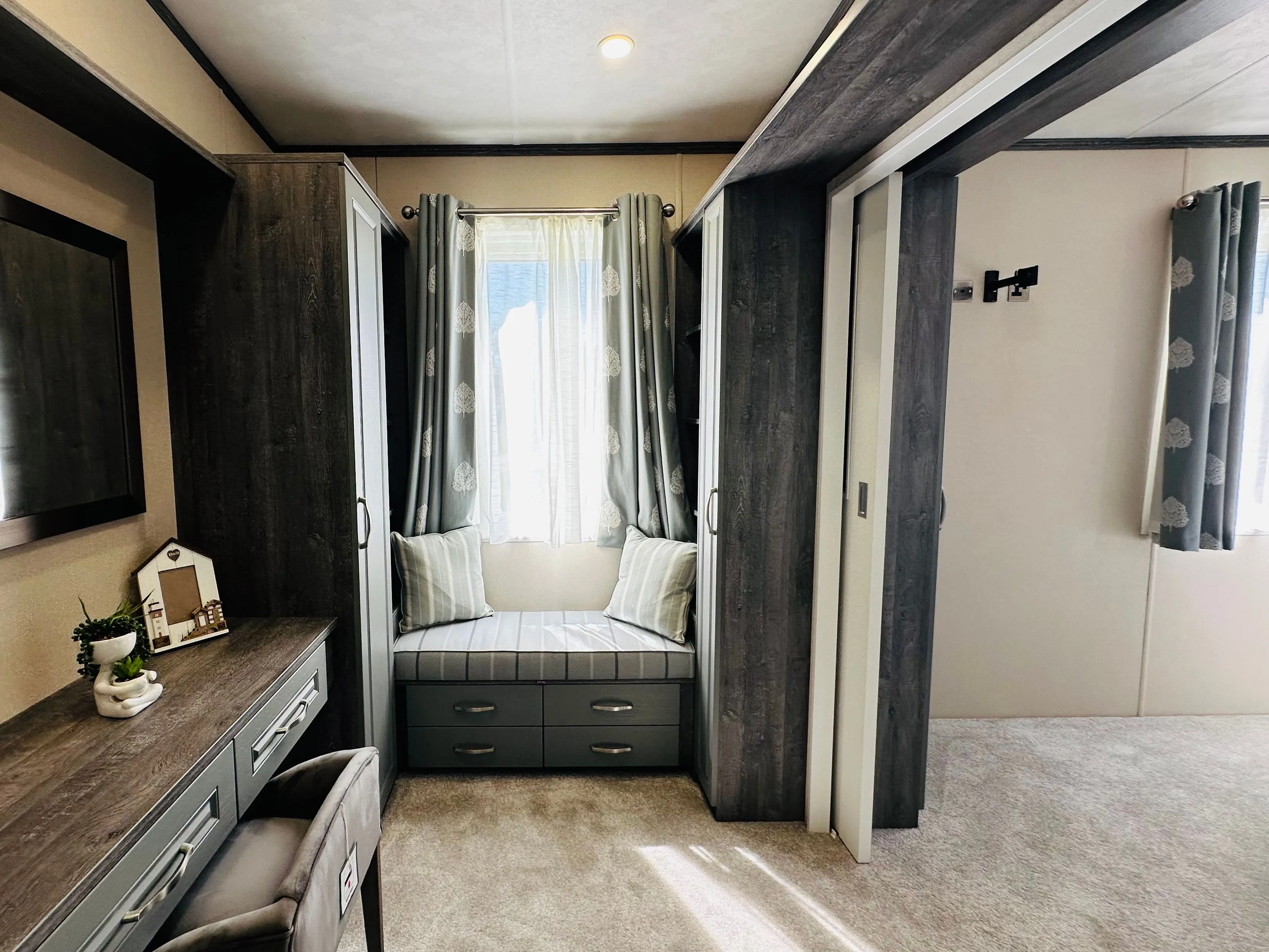 Modern bedroom dressing area with built-in wardrobes, vanity desk and cushioned window seat