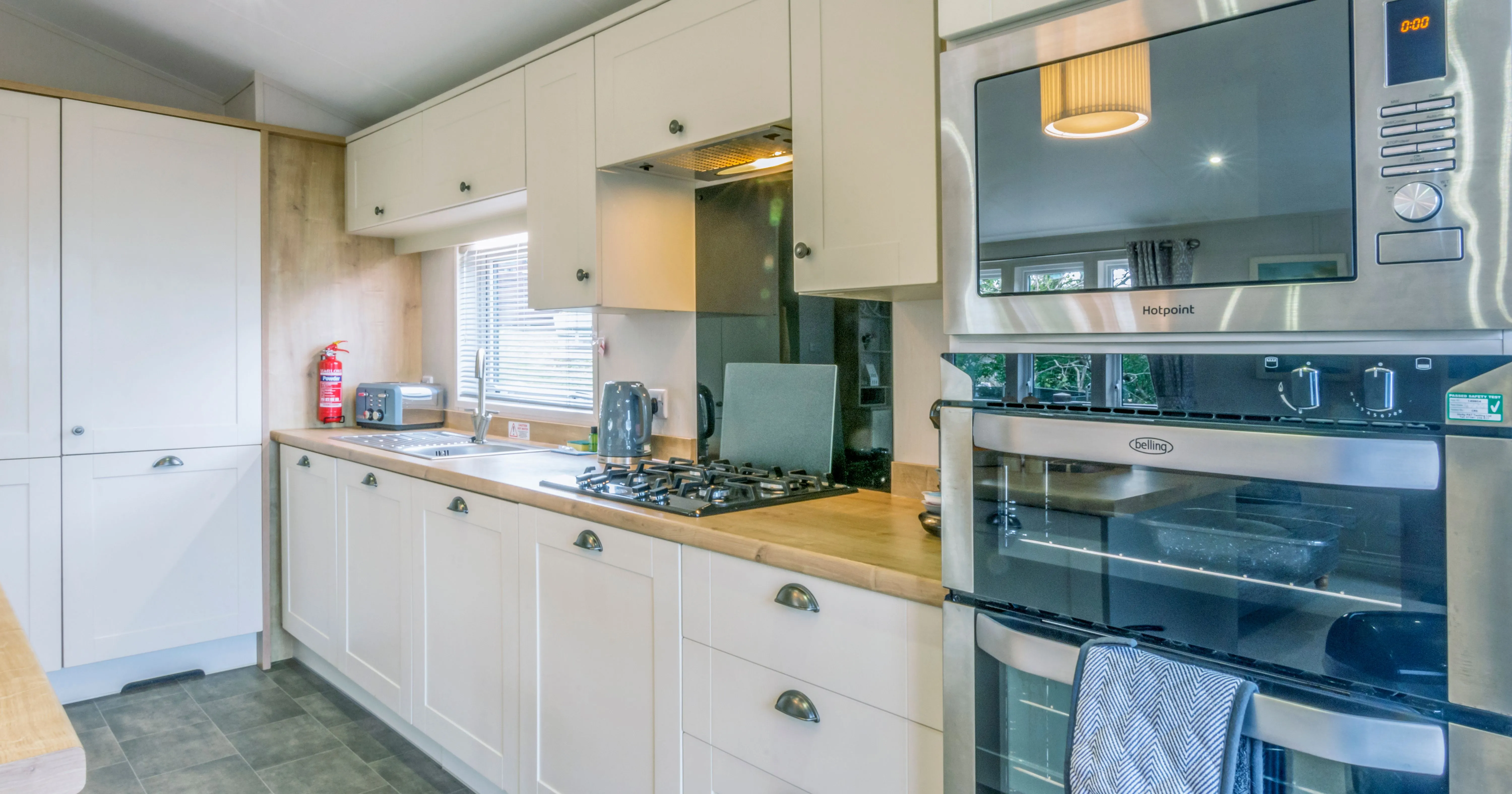 Modern galley kitchen with cream cabinets, wooden worktops, gas hob, double oven and built-in microwave