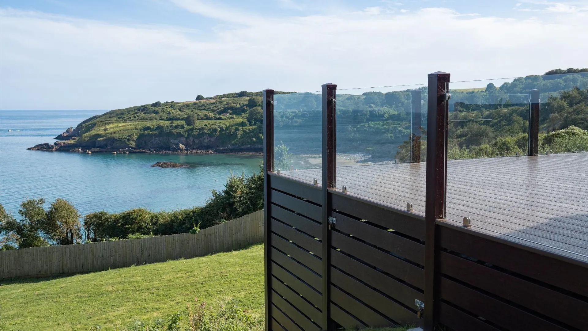Park-side lodge decking with glass balustrade overlooking cliff-top sea views at Riviera Bay, Devon