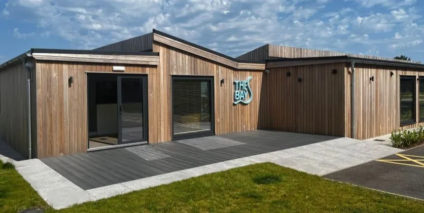 Exterior view of The Bay building with timber cladding, large windows and a decked entrance area