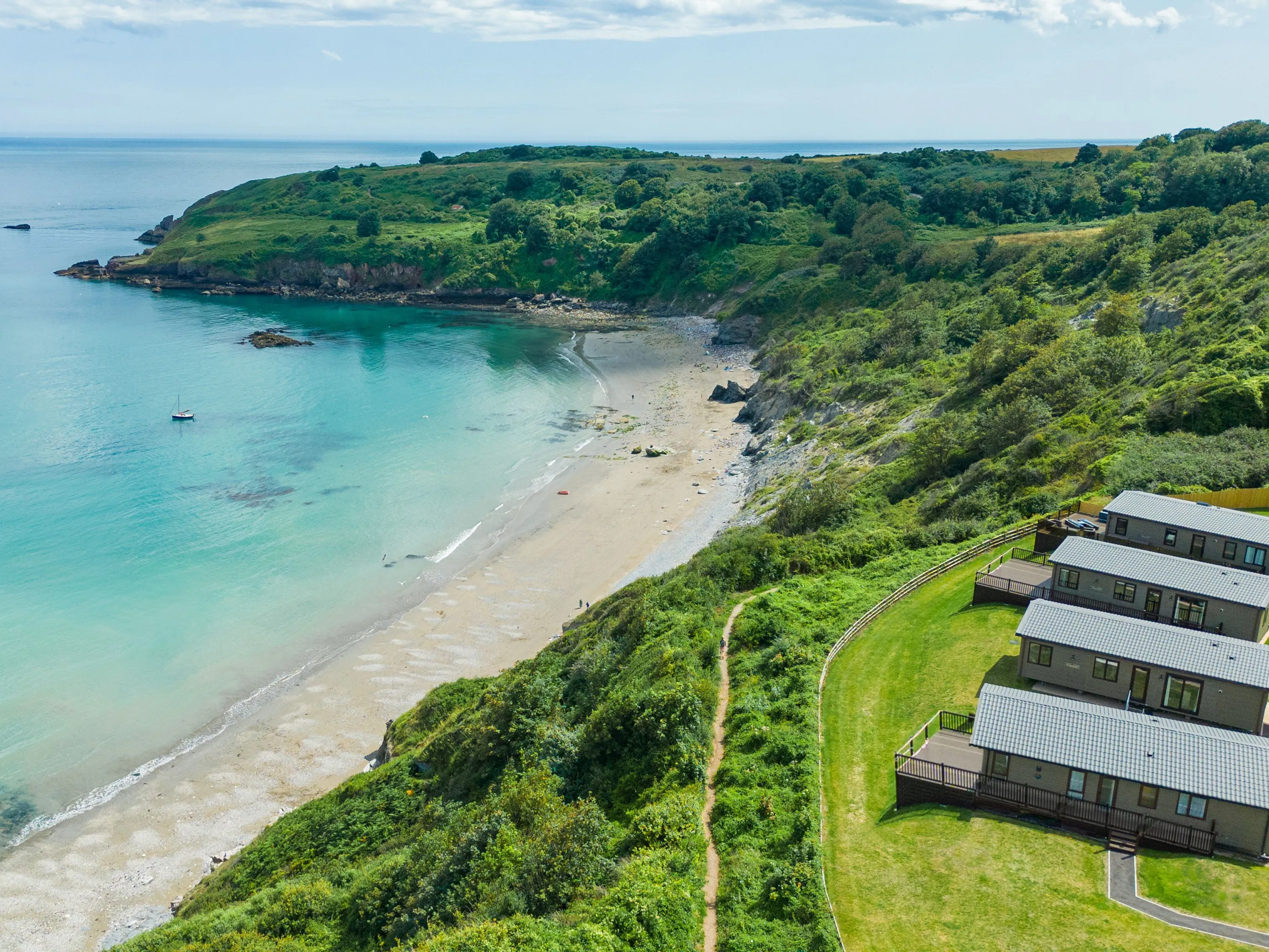 Drone view of Riviera Bay with a sandy beach, turquoise sea and holiday lodges on the clifftop