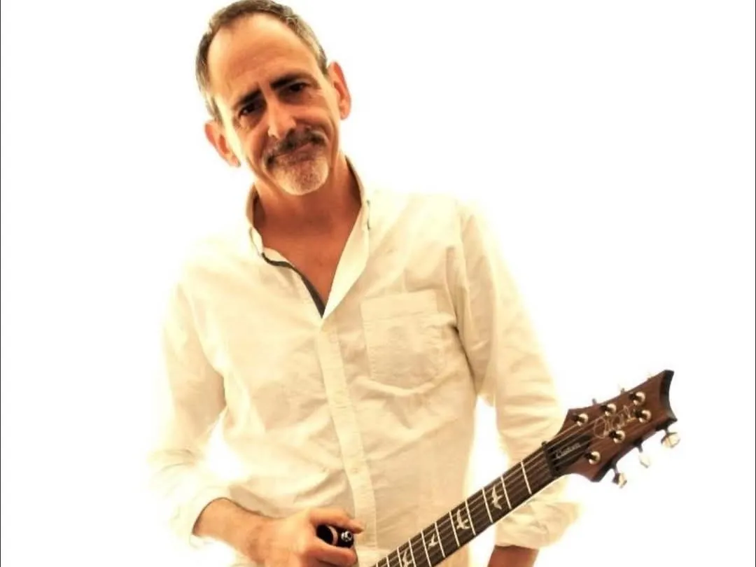 Nick Tilley standing with an electric guitar against a white background, promoting solo guitar and vocals.