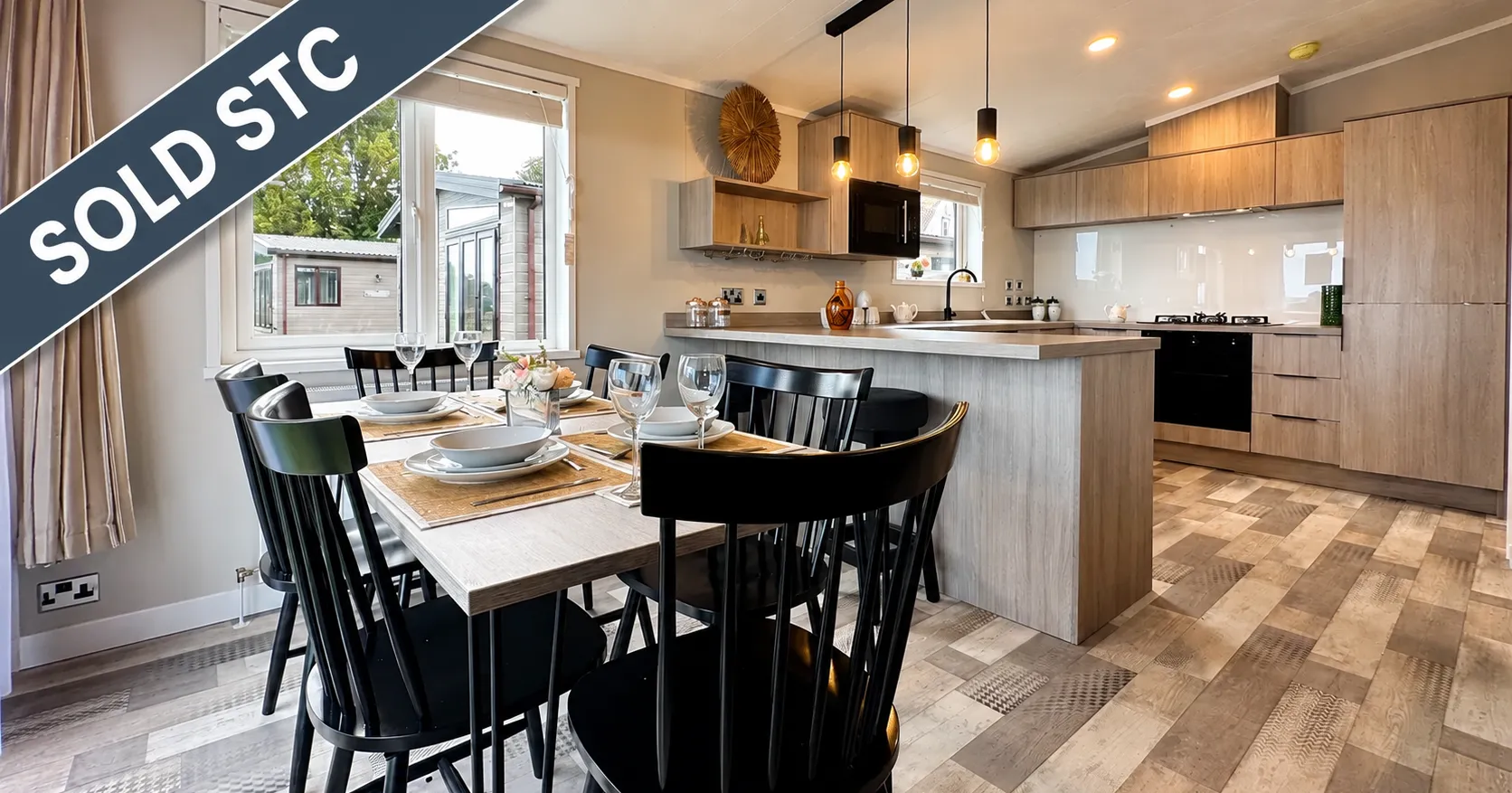 Modern open-plan kitchen and dining area in the Victory Faraday with a sold STC banner