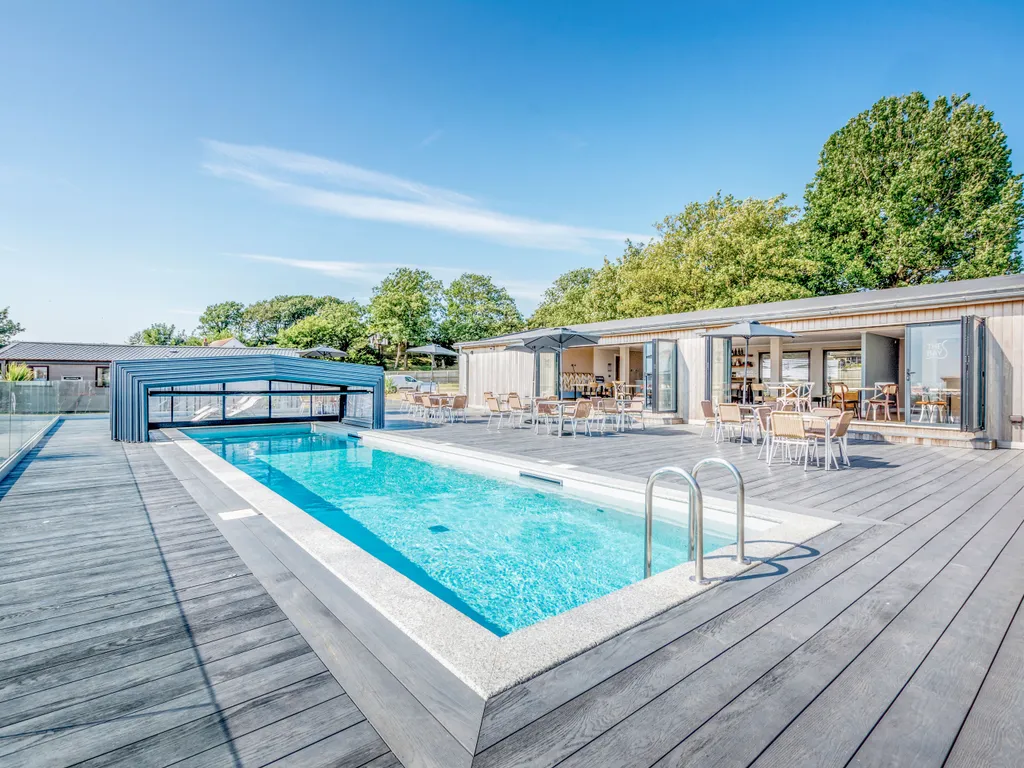 Outdoor swimming pool with a modern slatted canopy, timber decking and café terrace seating.