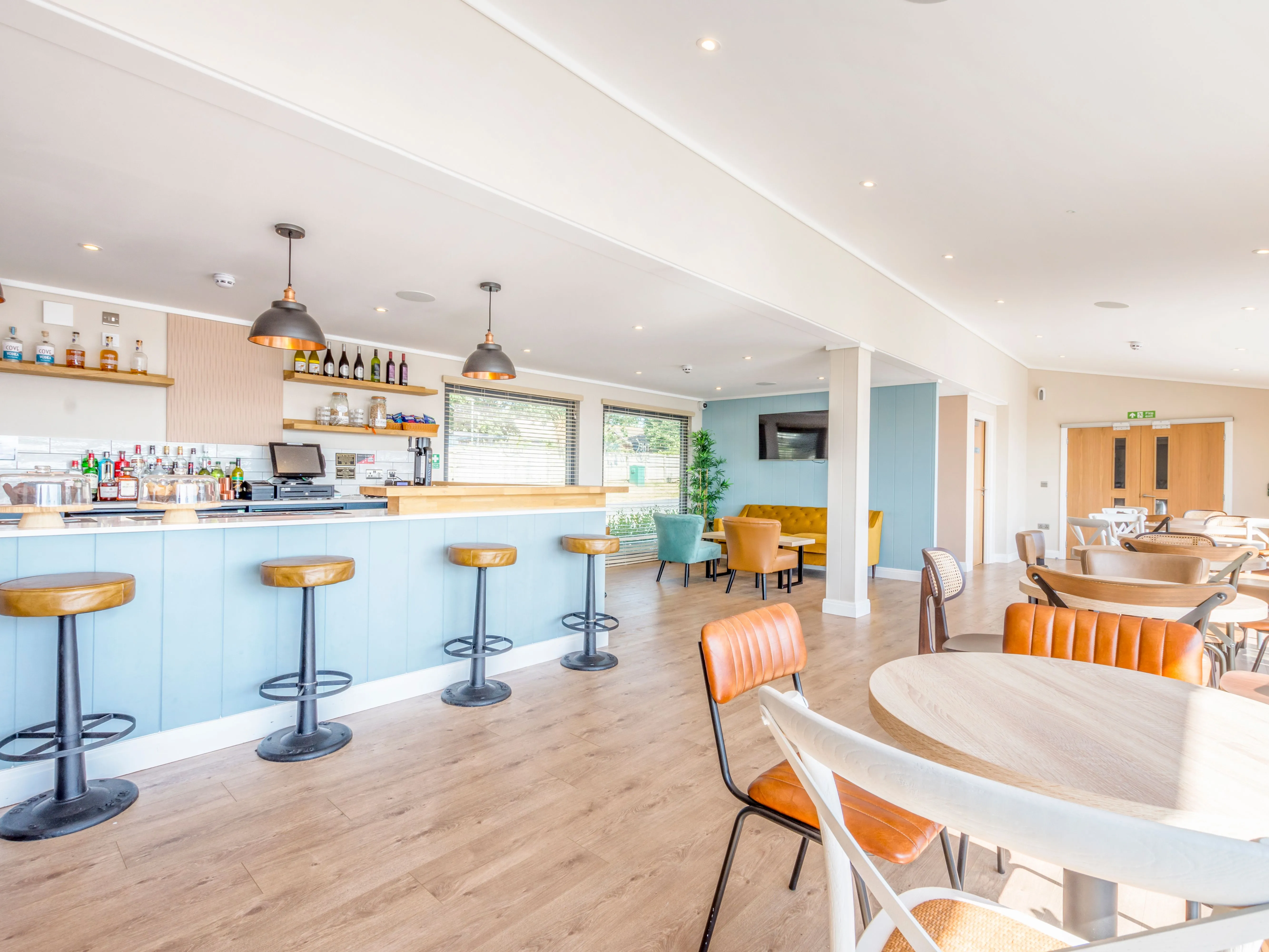 Bright modern café bar with pale blue counter, leather stools and dining tables