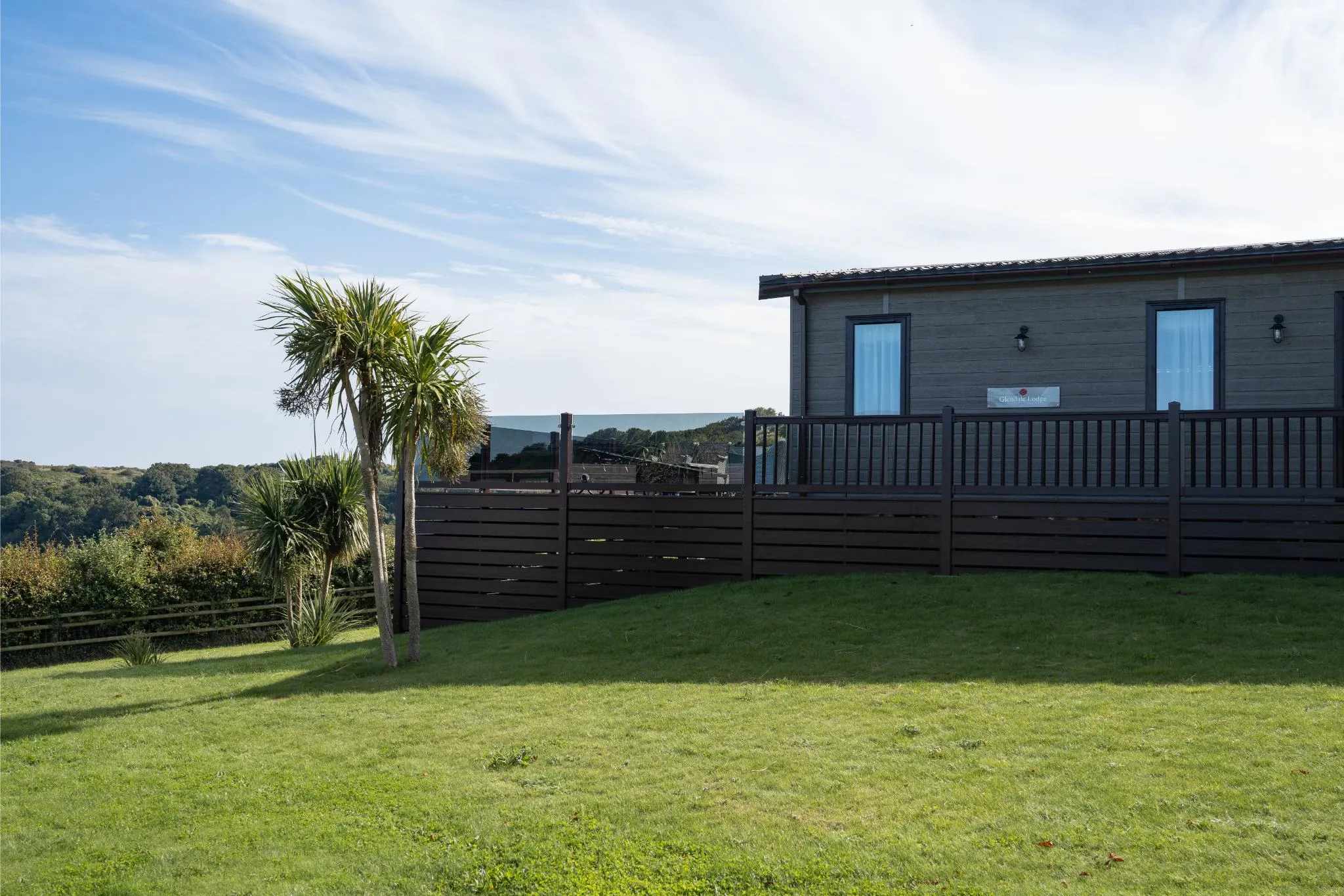 Clifftop lodge with decking and palm trees overlooking the sea in Devon