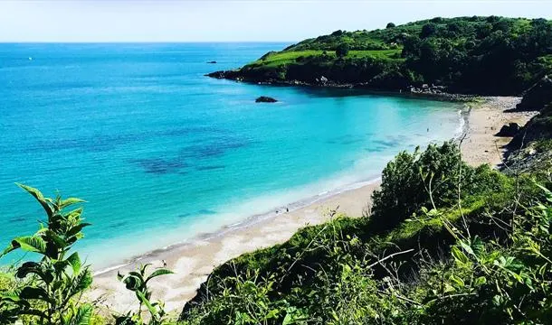 Turquoise sea and sandy beach at St Marys Bay with green cliffs