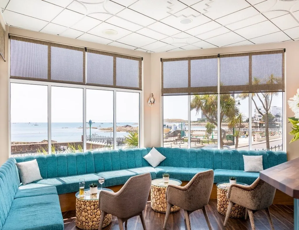 Stylish coastal bar lounge with turquoise seating, armchairs and sea views through large windows