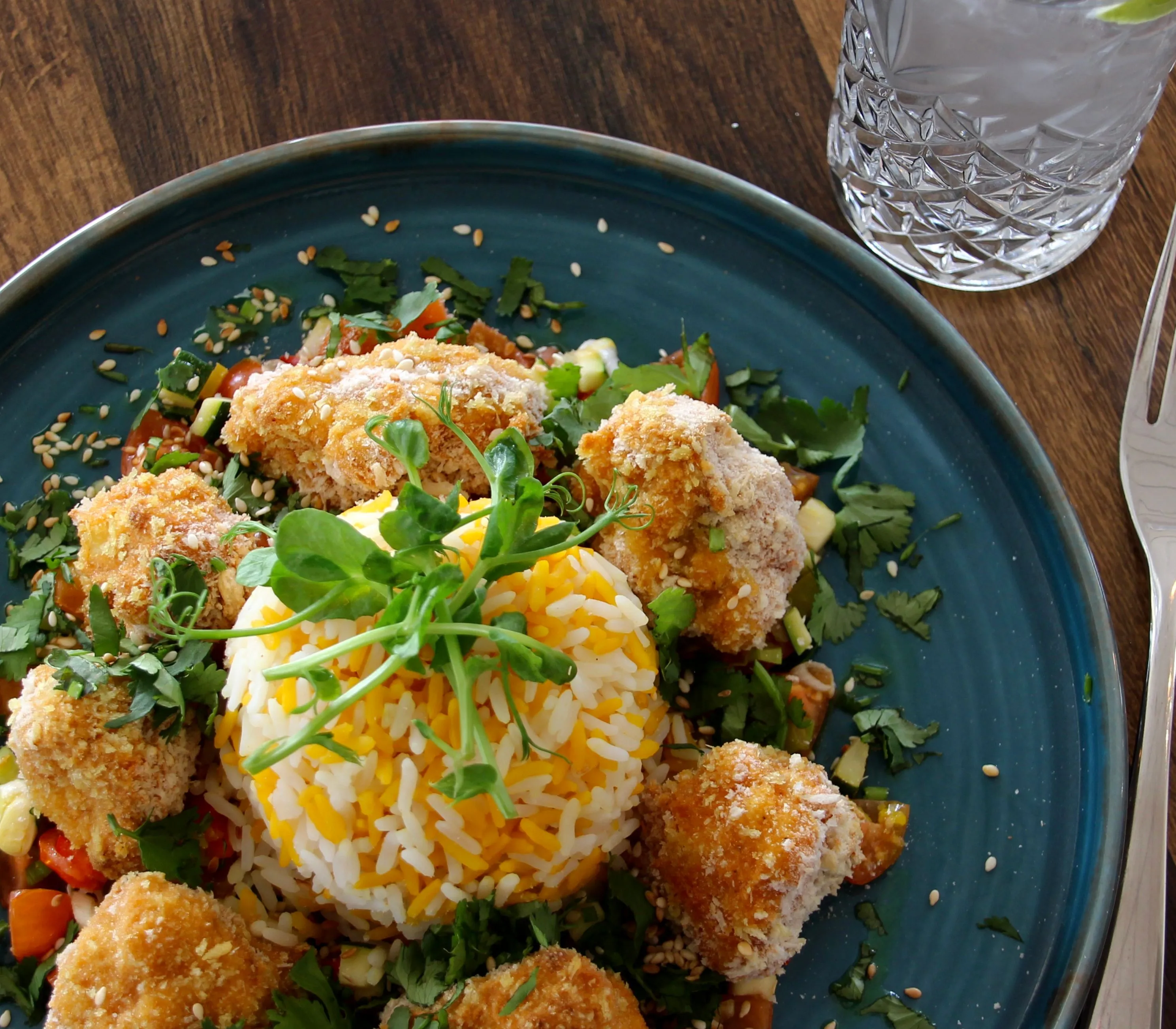 Breaded chicken pieces served with saffron rice, fresh herbs and salad on a blue plate at Palmers Restaurant