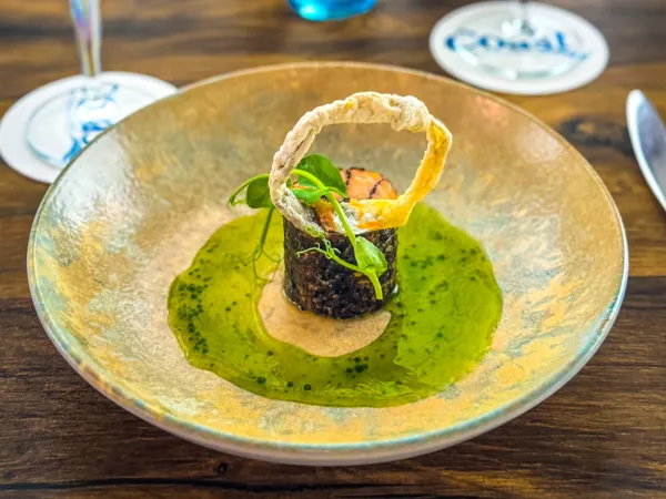 Elegantly plated fine dining dish with red and white wine on a wooden table at Palmers Restaurant.
