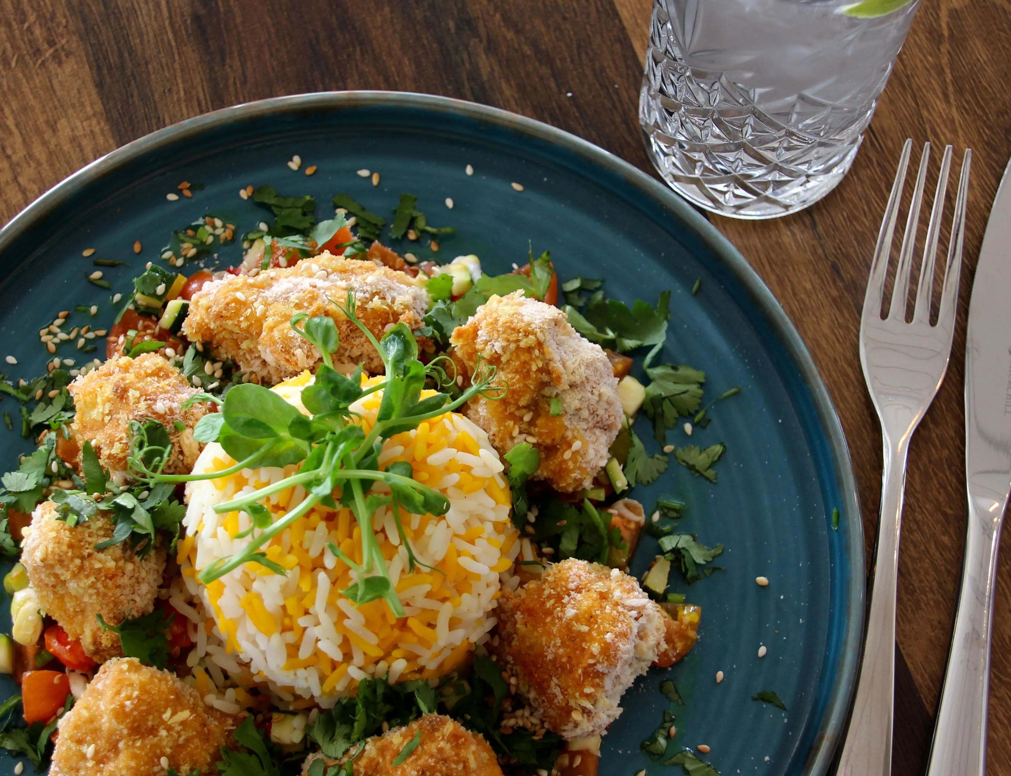 Crispy breaded chicken served with saffron rice, fresh herbs and vegetables on a blue plate at Palmers Restaurant