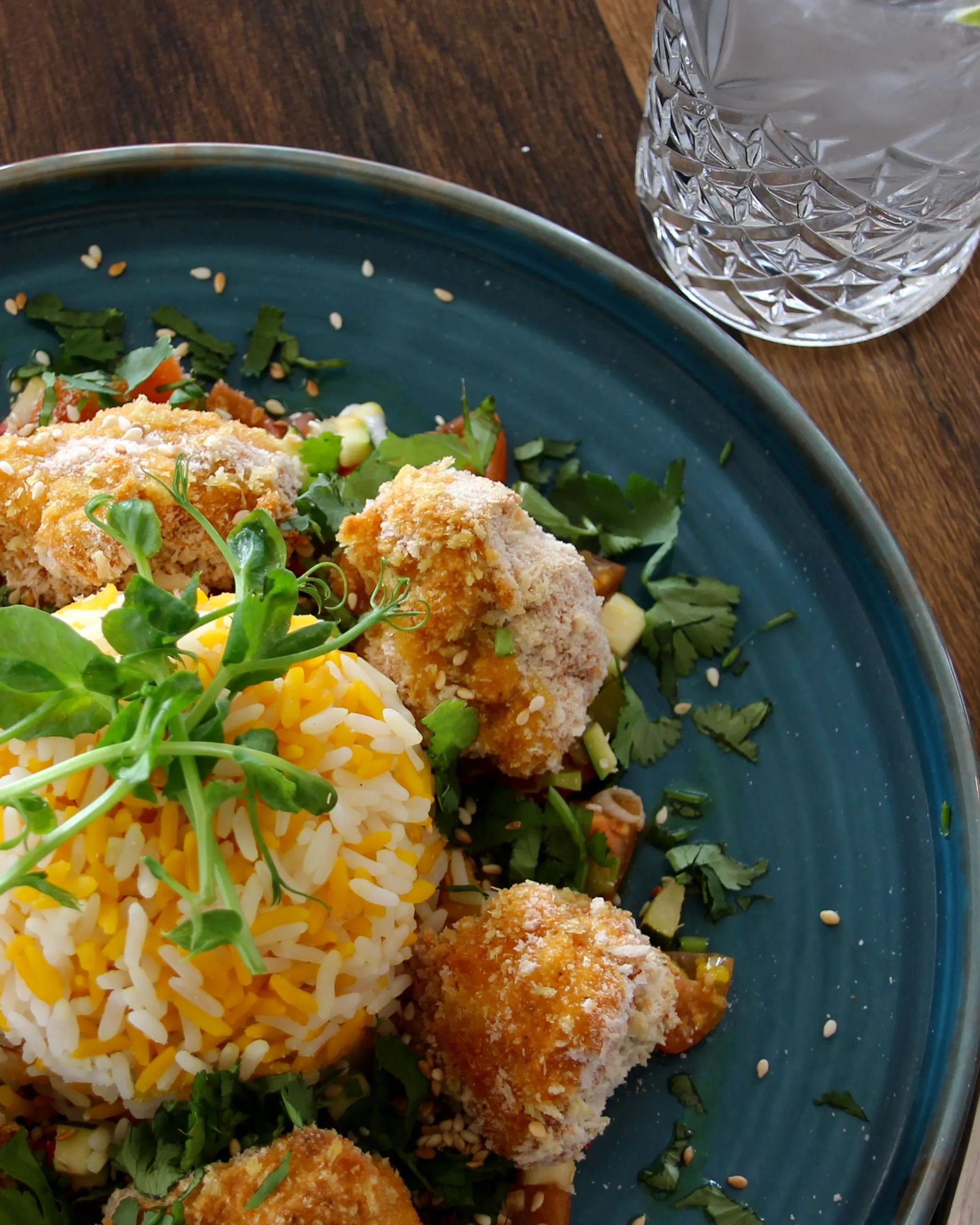 Crispy breaded chicken served with saffron rice, fresh herbs and vegetables on a blue plate at Palmers Restaurant