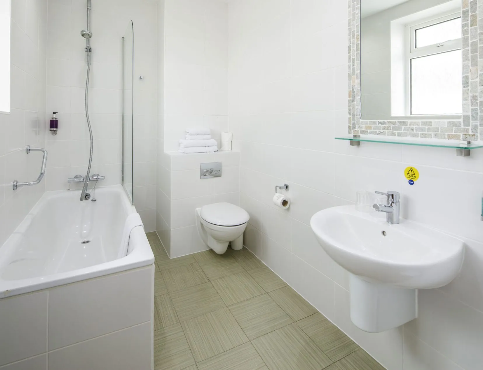 Bright modern bathroom with bath, overhead shower, wall-mounted sink and toilet