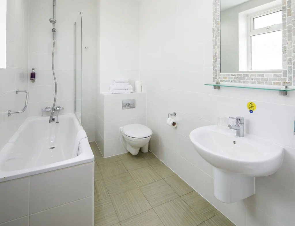 Bright modern bathroom with bath, overhead shower, wall-mounted sink and toilet
