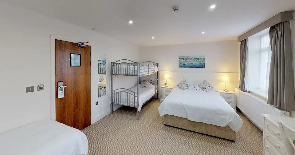 Family room for 5 with a double bed, bunk beds and a single bed in a bright, spacious bedroom