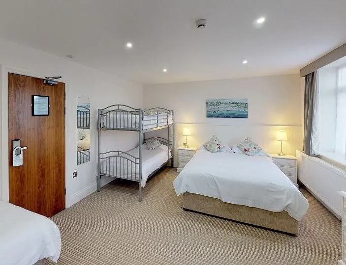Family room for 5 with a double bed, bunk beds and a single bed in a bright, spacious bedroom