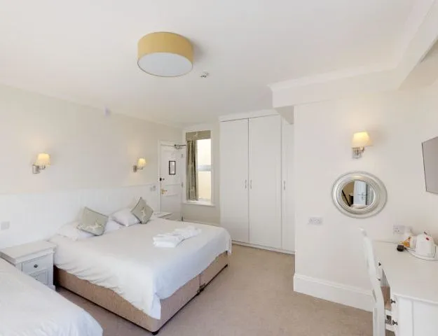 Bright family bedroom with a double bed and single bed, white décor, bedside table, wardrobe and dressing table