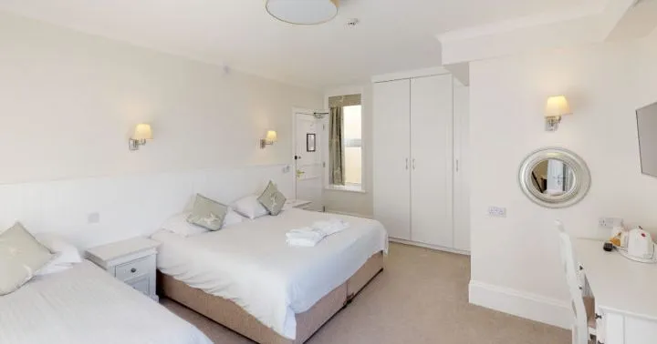 Bright family bedroom with a double bed and single bed, white décor, bedside table, wardrobe and dressing table