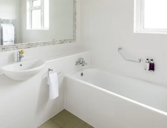 Bright modern bathroom with white bath, basin and large mirror