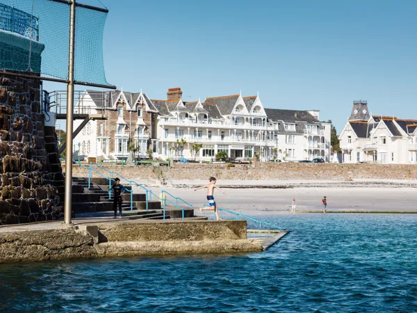 Boy jumping into the sea at Havre des Pas with beachfront buildings in the background