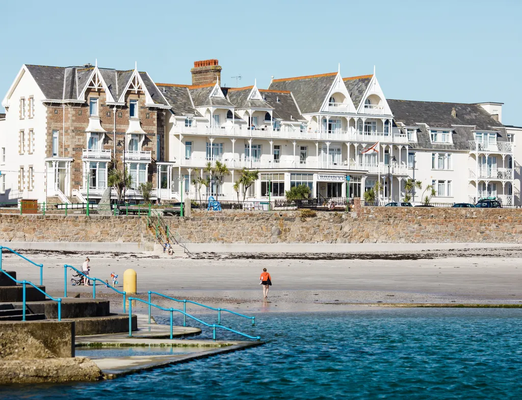 General view of Havre des Pas seafront with beachfront hotel buildings, sandy shore and sea pool steps in Jersey