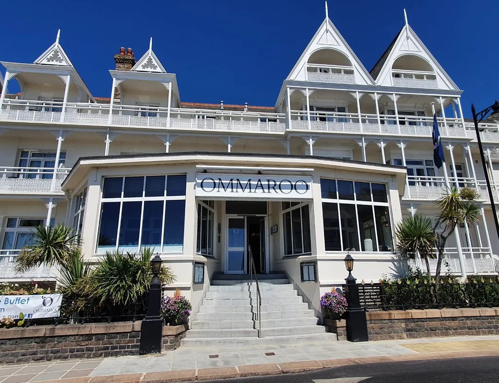 Front entrance of Ommaroo Hotel with white Victorian-style balconies and a bright blue sky