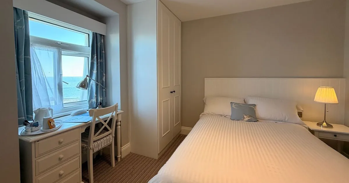 Single room with a double bed, desk by the window, and sea view