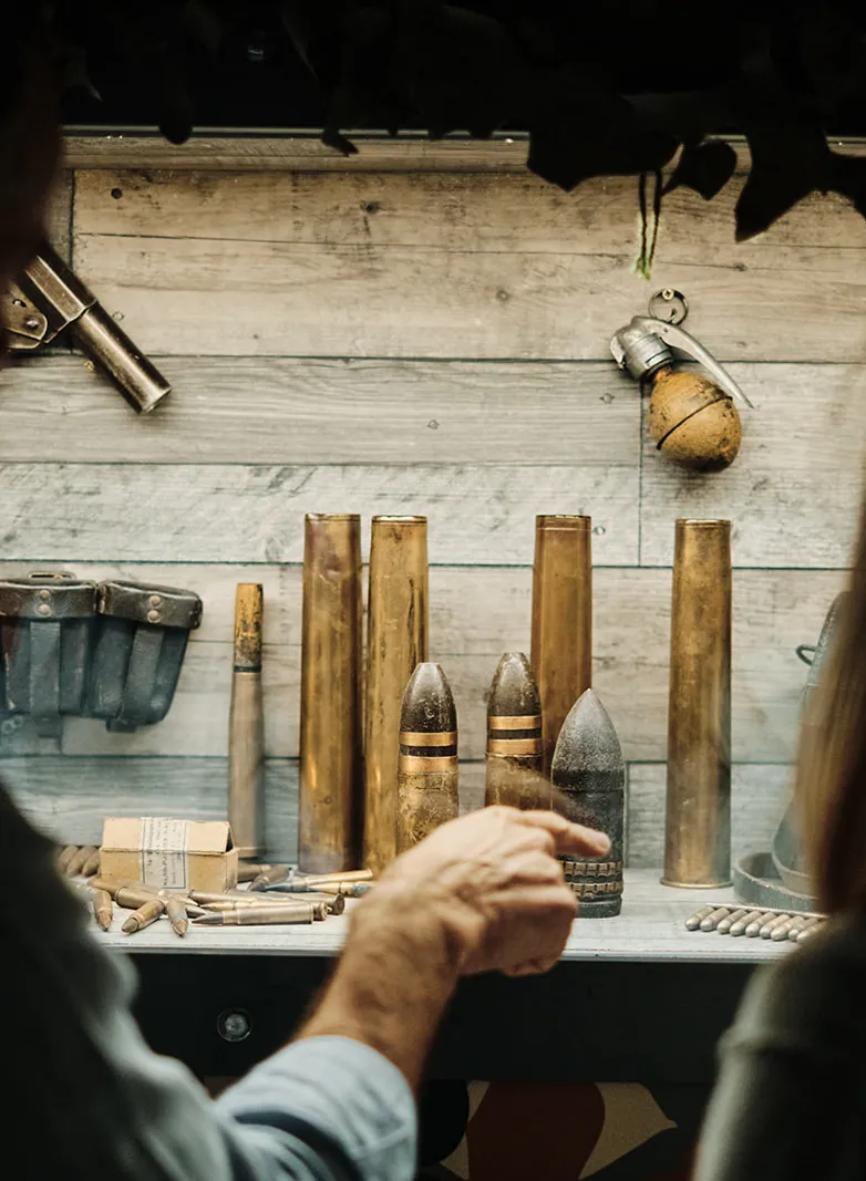 Two people looking at a display of vintage ammunition, artillery shells and grenades in a museum exhibit