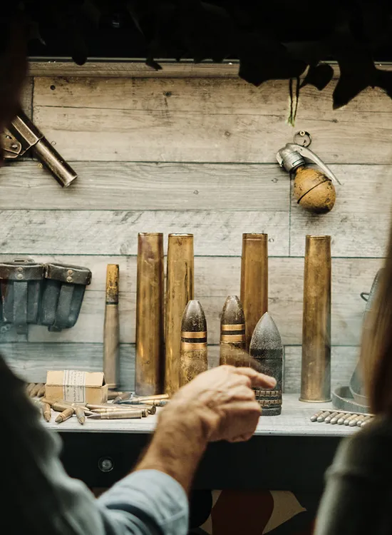 Two people looking at a display of vintage ammunition, artillery shells and grenades in a museum exhibit