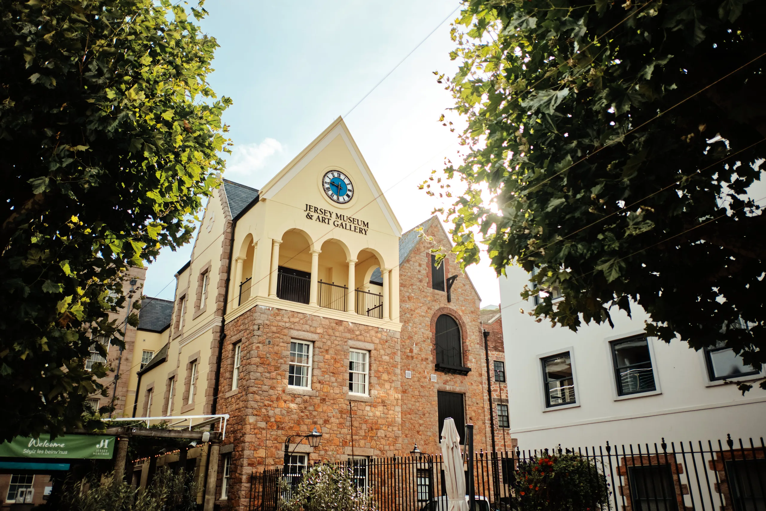 Jersey Museum & Art Gallery in Saint Helier framed by leafy trees on a sunny day