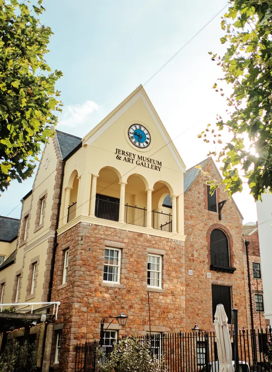 Jersey Museum & Art Gallery in Saint Helier framed by leafy trees on a sunny day