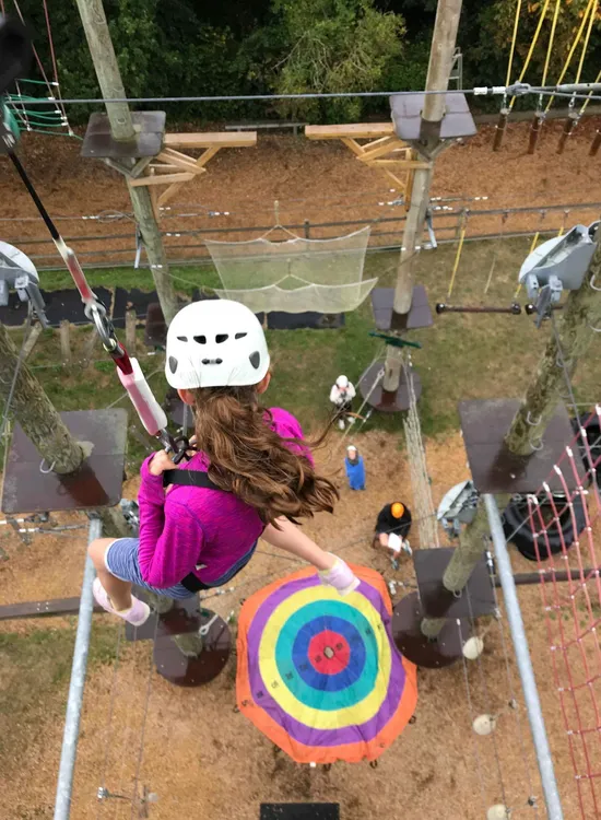 Child wearing a helmet and harness on a high ropes course at Valley Adventure Centre