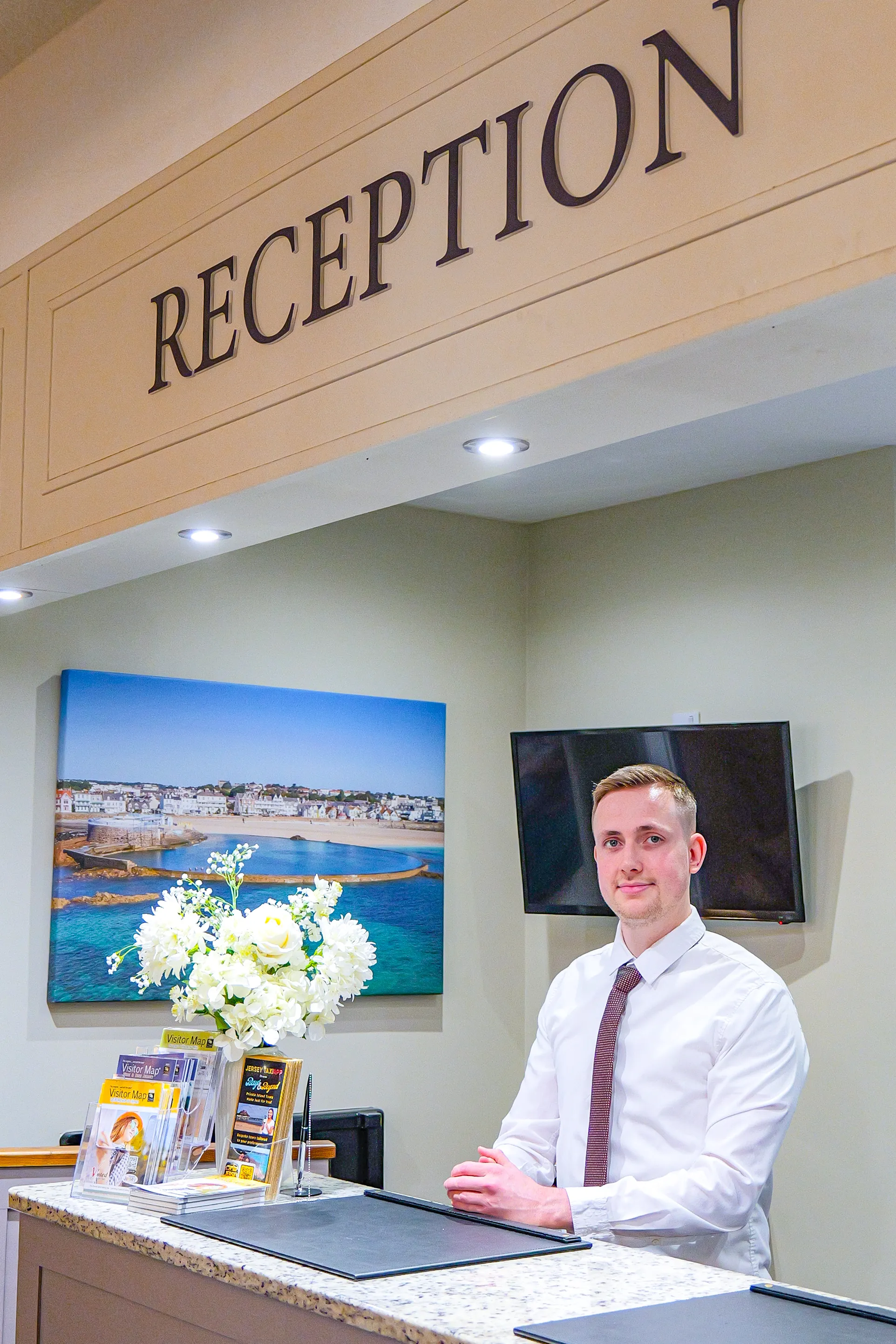 Reception desk at Ommaroo Hotel with a staff member standing behind the counter