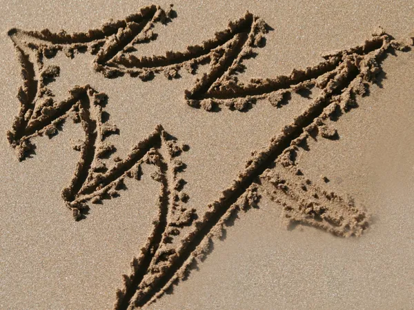 Decorative arrows drawn in wet sand on a beach, all pointing upwards and to the right.