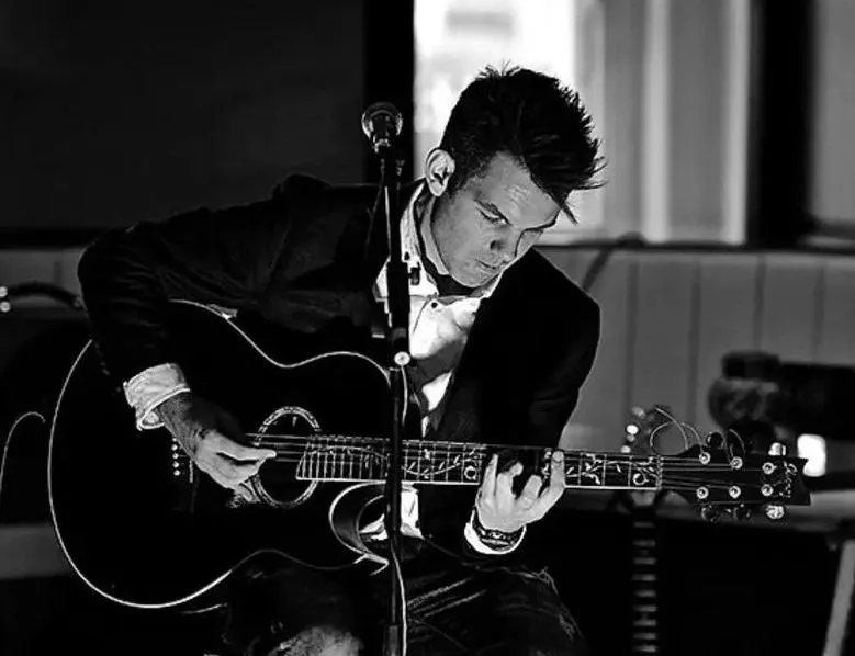 Matt MCManus playing an acoustic guitar during a live performance