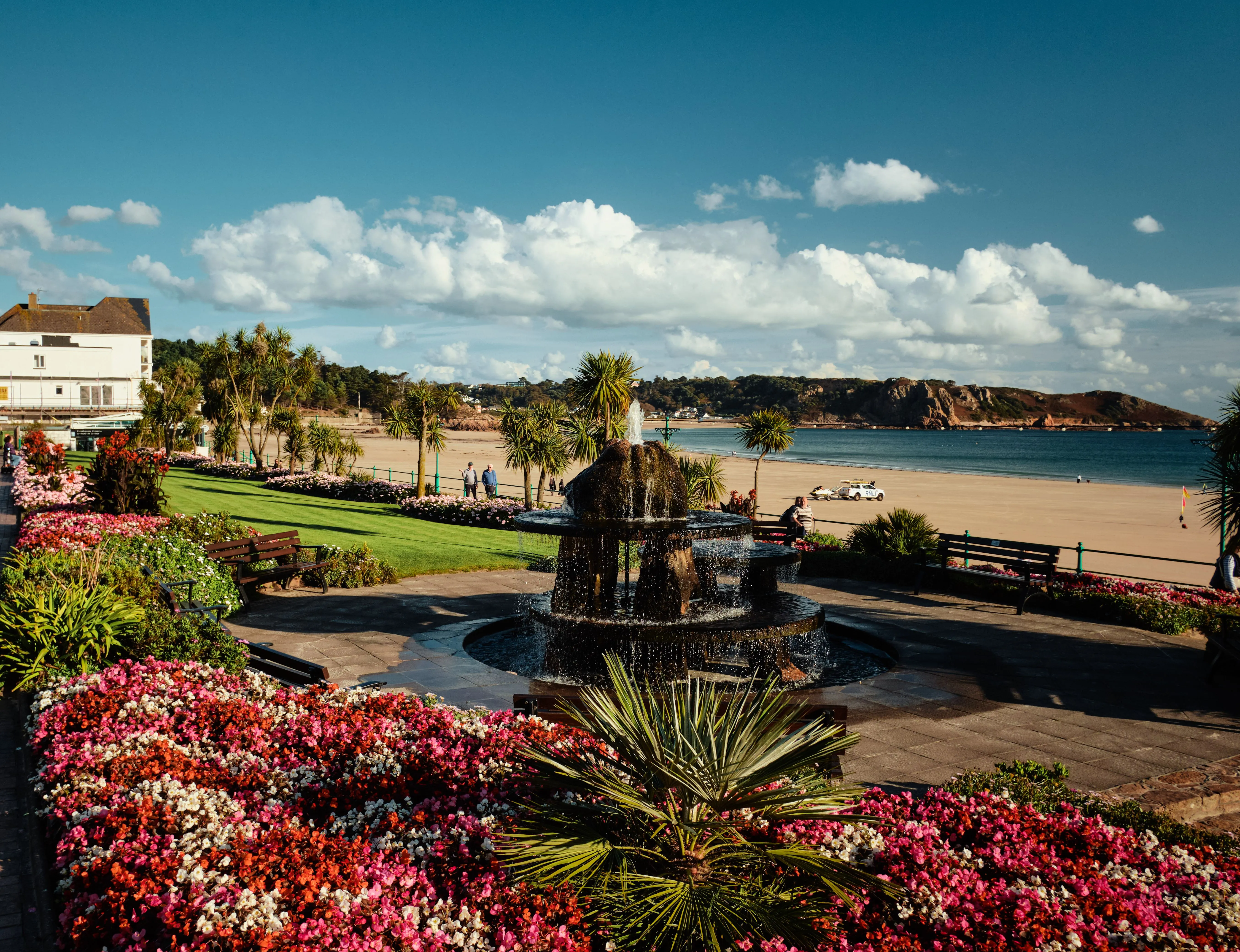 Colourful flower gardens and a fountain overlooking St Brelade's Bay beach in Jersey.