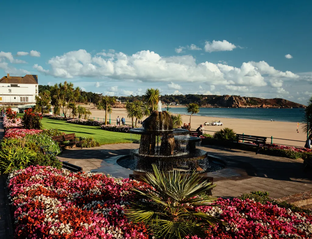 Colourful flower gardens and a fountain overlooking St Brelade's Bay beach in Jersey.