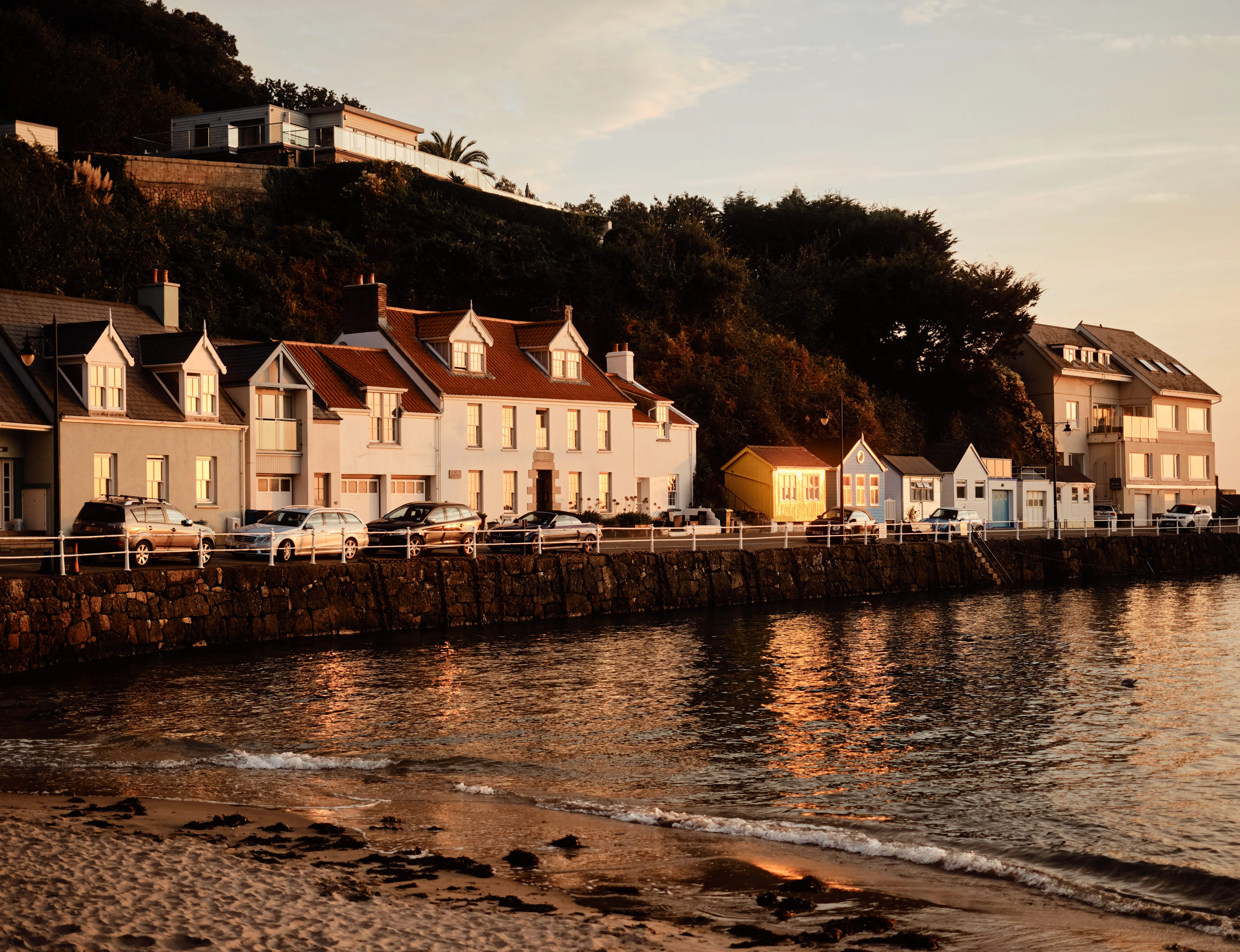 Golden-hour view of waterfront houses and a sandy beach at Rozel Bay
