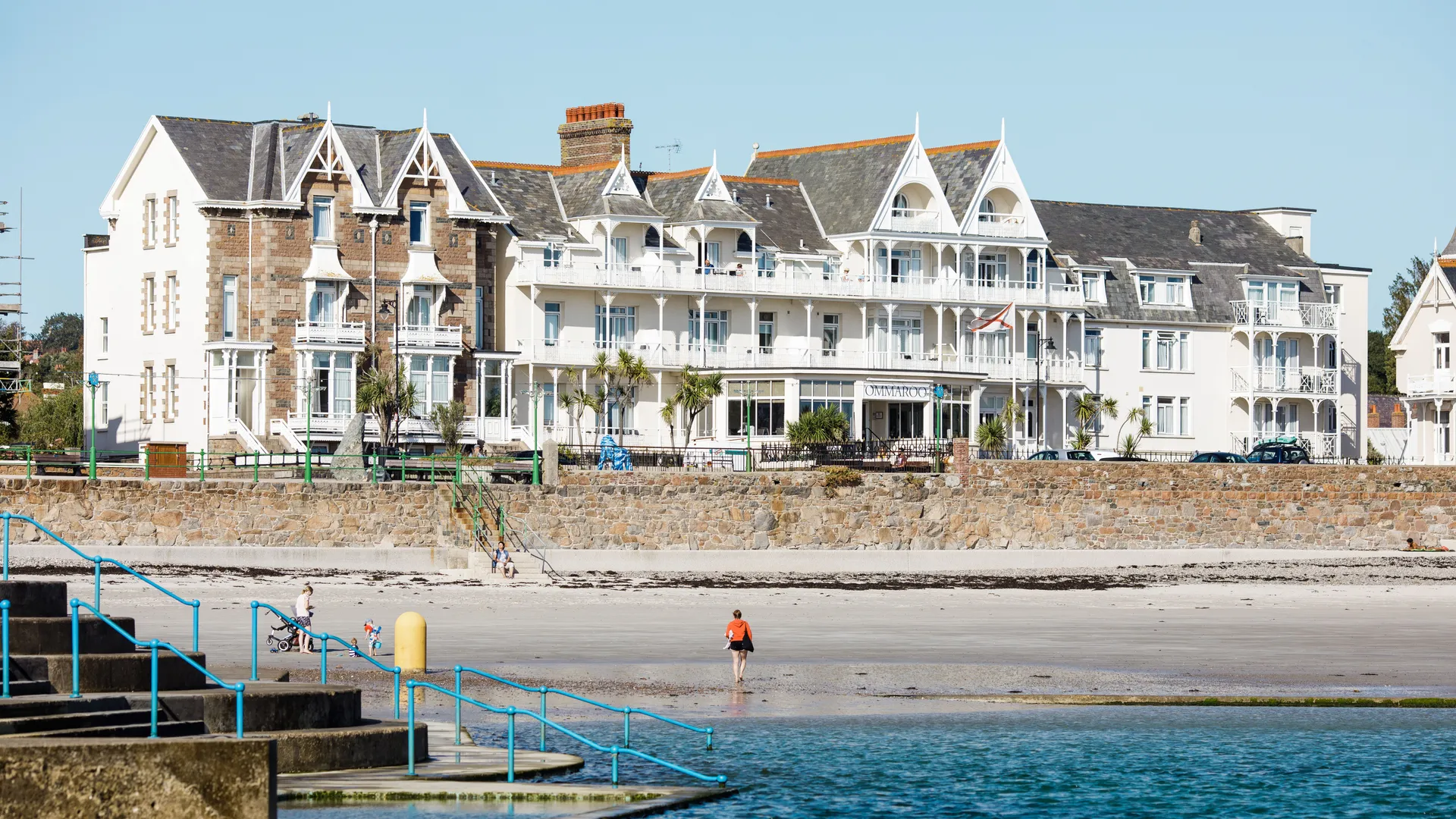 Seafront hotel and elegant Victorian-style buildings overlooking a sandy beach and bathing steps on a clear day