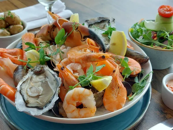 Seafood platter with prawns, oysters, mussels, crab claw and lemon wedges, served with salad and potatoes