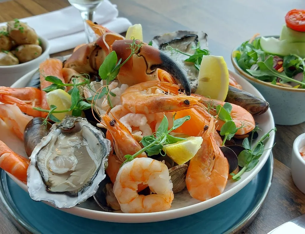 Seafood platter with prawns, oysters, mussels, crab claw and lemon wedges, served with salad and potatoes