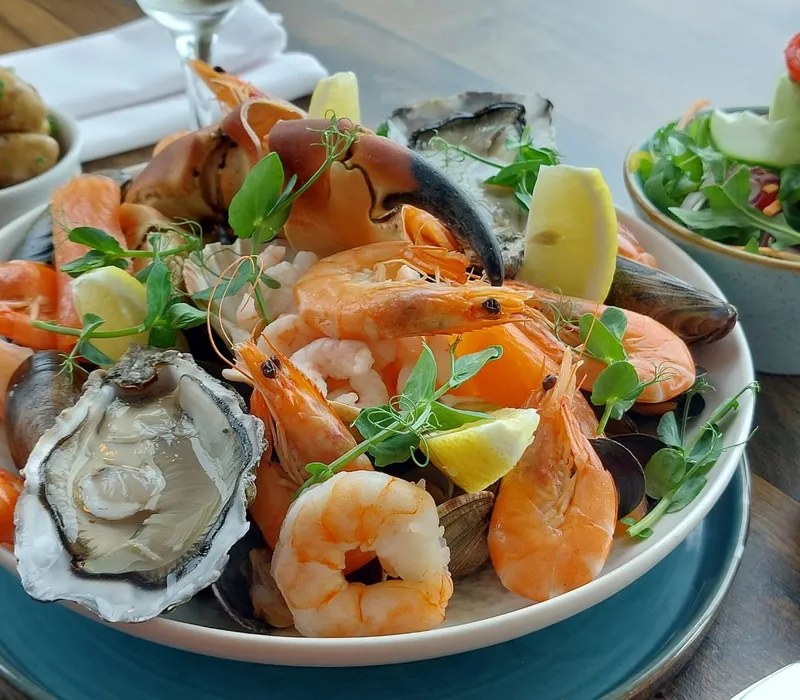 Seafood platter with prawns, oysters, mussels, crab claw and lemon wedges, served with salad and potatoes