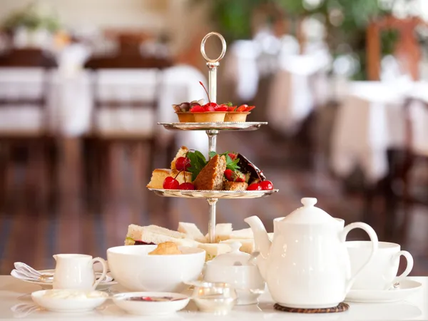 Afternoon tea set with sandwiches, cakes and fruit on a tiered stand in an elegant restaurant