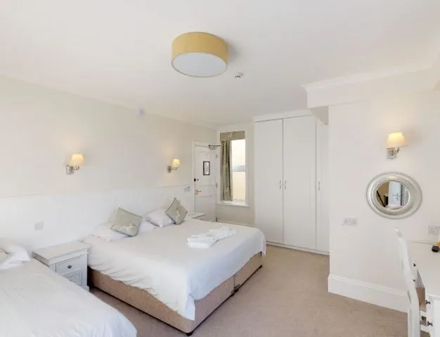Bright family hotel room with a double bed, single bed, wardrobe and dressing table