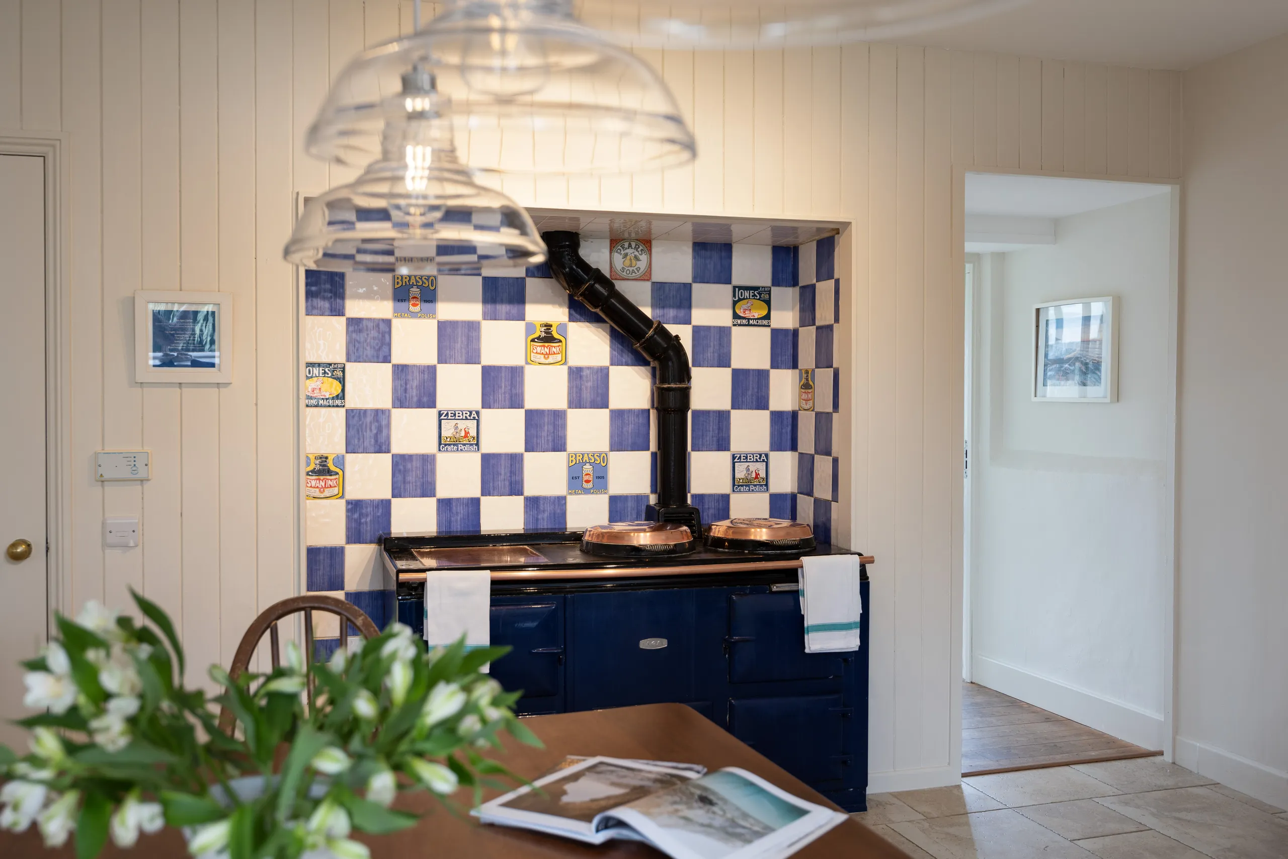 Country kitchen with blue range cooker, blue-and-white check tiled alcove and glass pendant lights