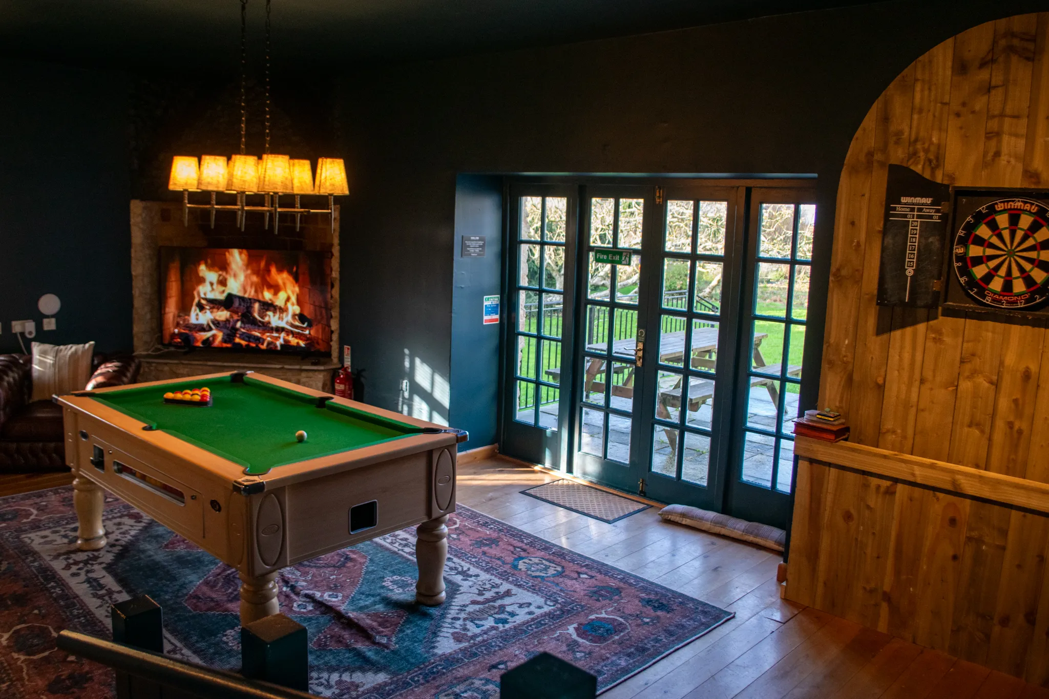 Cosy snug and games room with pool table, open fireplace, dartboard and French doors to garden